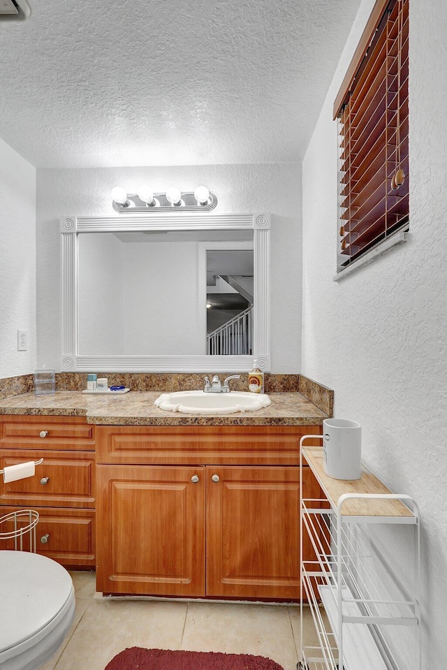 bathroom with a textured wall, a textured ceiling, and tile patterned flooring