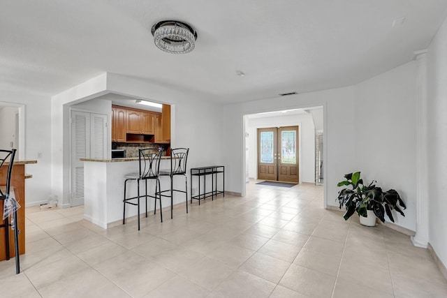 kitchen with visible vents, a breakfast bar, backsplash, a peninsula, and light tile patterned floors