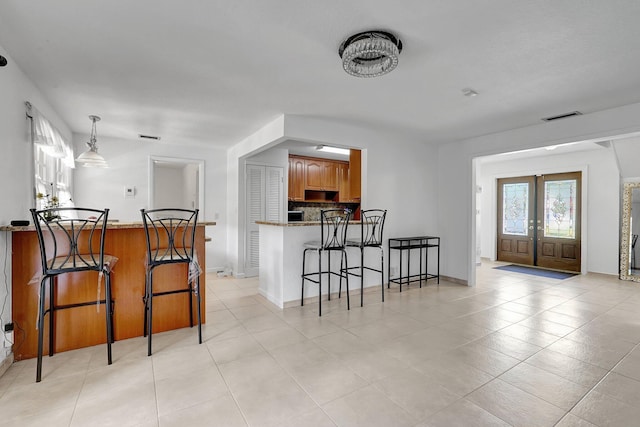 10476 SW 52nd St, Cooper City, FL 33328 - kitchen with a peninsula, a breakfast bar area, backsplash, french doors, and brown cabinets