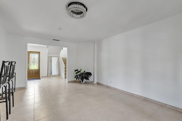 spare room featuring visible vents, baseboards, and stairway