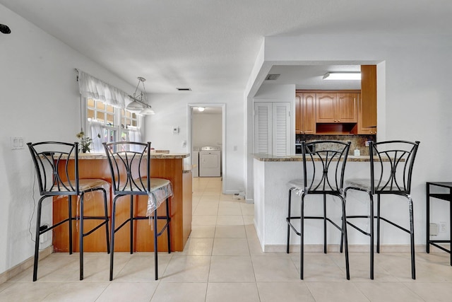 kitchen featuring washing machine and clothes dryer, a peninsula, and a breakfast bar area