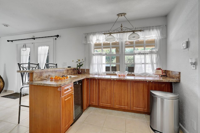 kitchen featuring a wealth of natural light, a kitchen breakfast bar, brown cabinets, and beverage cooler