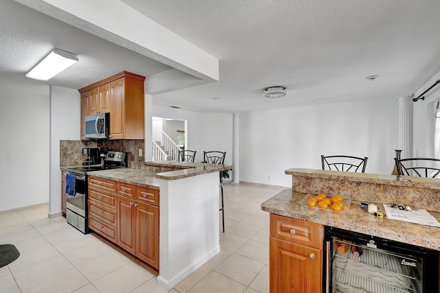 kitchen featuring backsplash, wine cooler, stainless steel appliances, light tile patterned flooring, and a textured ceiling