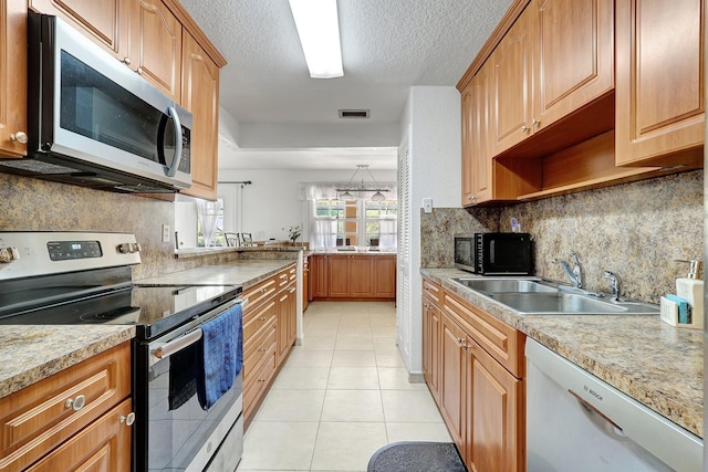 kitchen featuring light countertops, light tile patterned floors, stainless steel appliances, a textured ceiling, and a sink