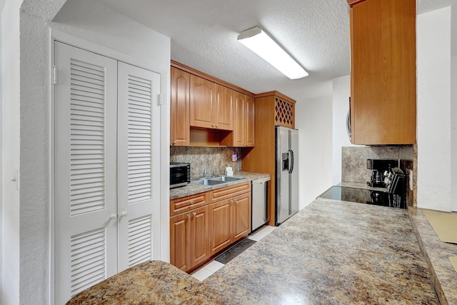 kitchen with backsplash, light countertops, stainless steel appliances, a textured ceiling, and a sink