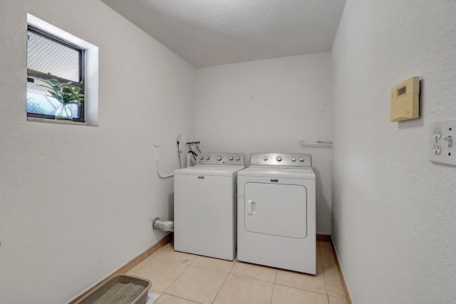 clothes washing area with light tile patterned floors, baseboards, independent washer and dryer, and laundry area