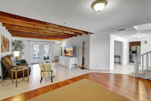 living room featuring stairway, visible vents, light wood-style floors, french doors, and beamed ceiling