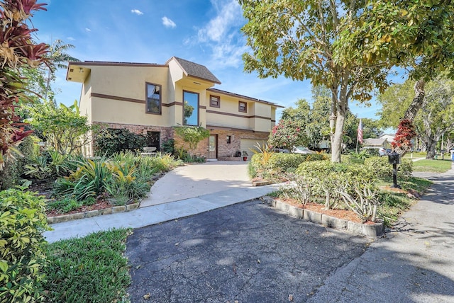 view of front of home with stucco siding, brick siding, and driveway