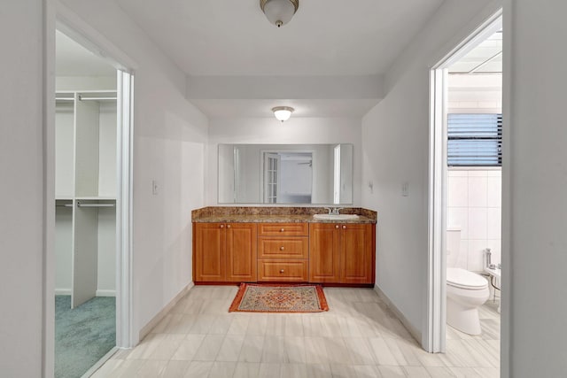 bathroom with baseboards, toilet, and vanity