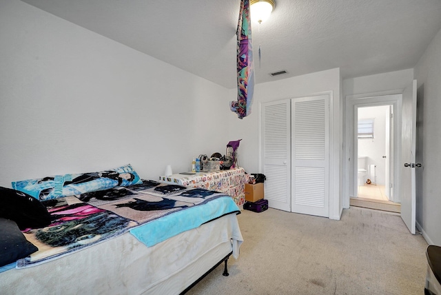 bedroom with a closet, carpet floors, a textured ceiling, and visible vents