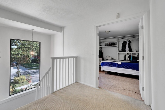 bedroom with a textured ceiling, a walk in closet, and baseboards