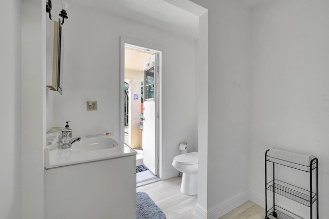 bathroom with toilet, vanity, and baseboards