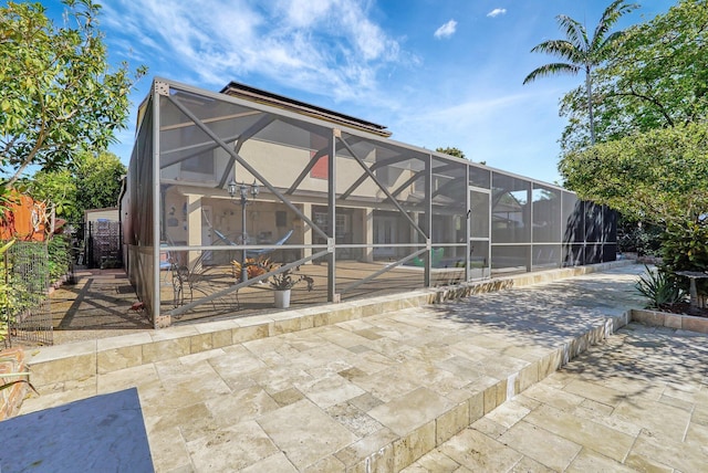 back of house featuring glass enclosure and a patio area