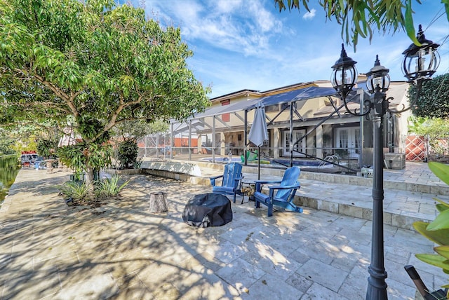 view of patio / terrace featuring glass enclosure and a pool