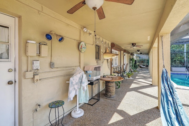 view of patio featuring an outdoor pool, glass enclosure, and ceiling fan