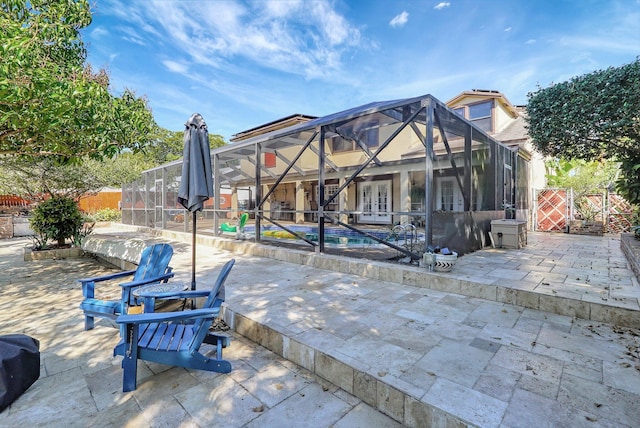 rear view of house with glass enclosure, a fenced in pool, a patio area, and fence