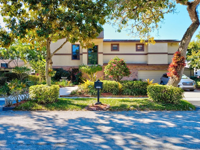 view of front of home with stucco siding, brick siding, and an attached garage