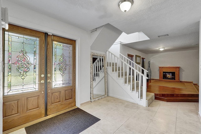 entryway featuring stairway, light tile patterned floors, a healthy amount of sunlight, and visible vents