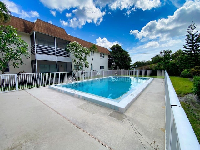 pool with a patio area and fence