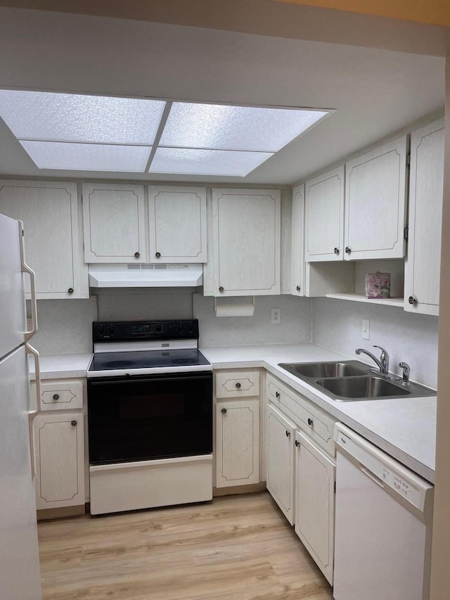 kitchen featuring under cabinet range hood, light countertops, light wood-type flooring, white appliances, and a sink