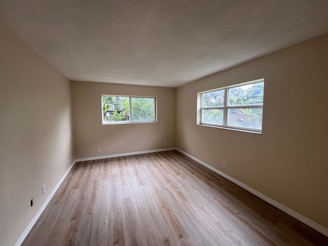 spare room with a textured ceiling, baseboards, and wood finished floors