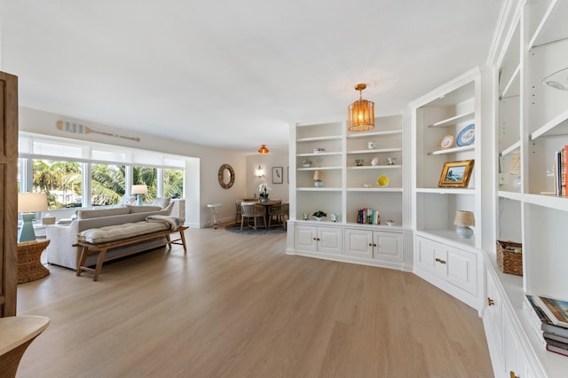 sitting room featuring baseboards, light wood-style floors, and built in shelves