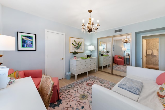 bedroom with wood finished floors, visible vents, a closet, and a chandelier