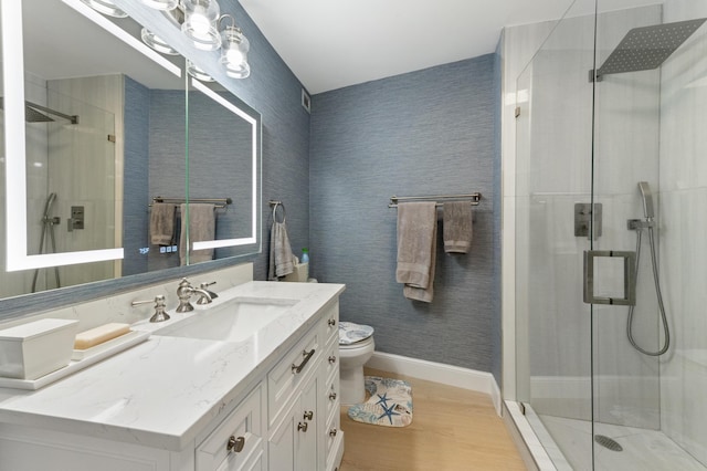 full bathroom featuring wallpapered walls, toilet, vanity, and a stall shower