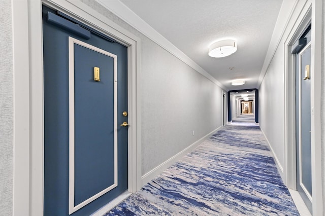 hallway with a textured ceiling, crown molding, and baseboards