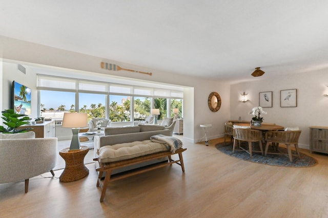 living room featuring light wood-style flooring, visible vents, and baseboards