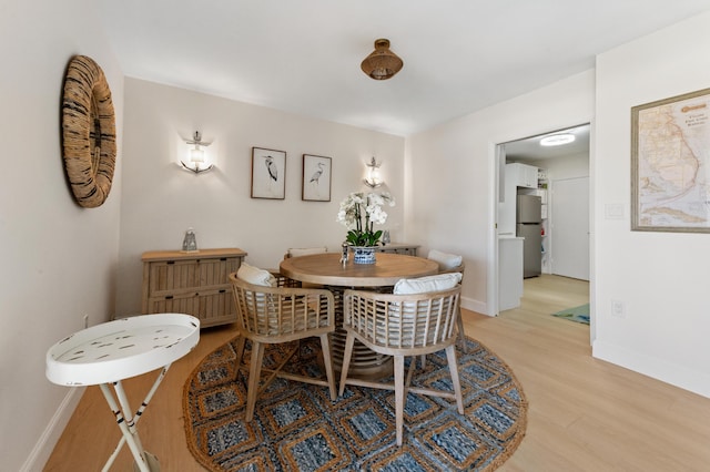 dining space featuring light wood-style flooring and baseboards