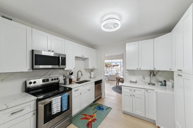 kitchen with white cabinets, light wood-style floors, appliances with stainless steel finishes, and a sink