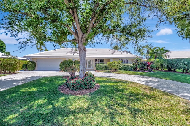 ranch-style house with a front yard, decorative driveway, and a garage