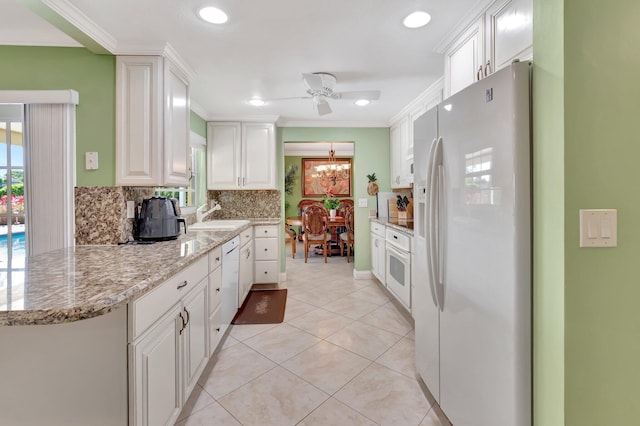 kitchen with white appliances, light tile patterned floors, decorative backsplash, white cabinets, and crown molding