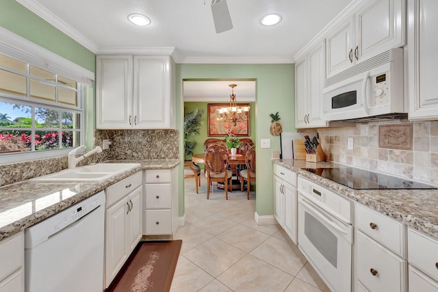 kitchen featuring white appliances, white cabinets, crown molding, and a sink