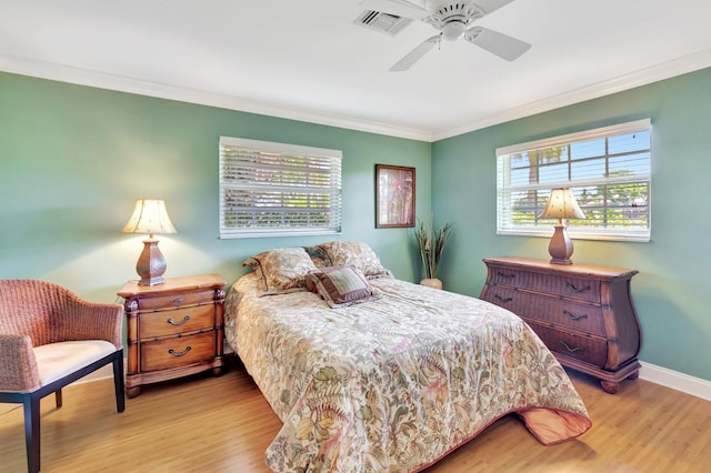 bedroom featuring crown molding, wood finished floors, visible vents, and baseboards