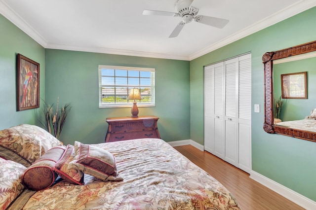 bedroom featuring a closet, baseboards, wood finished floors, and crown molding