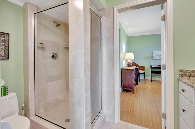 full bathroom with a shower stall, toilet, crown molding, and wood finished floors