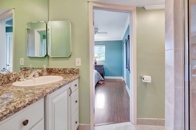 ensuite bathroom featuring crown molding, baseboards, ceiling fan, ensuite bathroom, and vanity