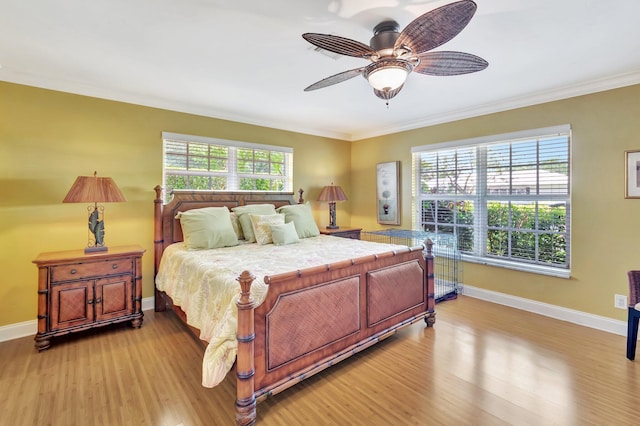 bedroom featuring multiple windows, baseboards, light wood-style floors, and ornamental molding