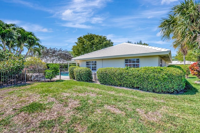 view of home's exterior with a yard, fence, stucco siding, and a tiled roof