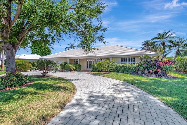 ranch-style house featuring a front lawn, decorative driveway, and stucco siding