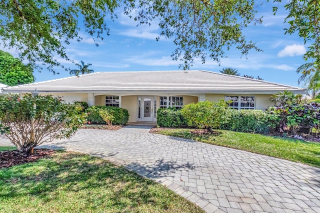 ranch-style house with stucco siding, decorative driveway, and a front lawn