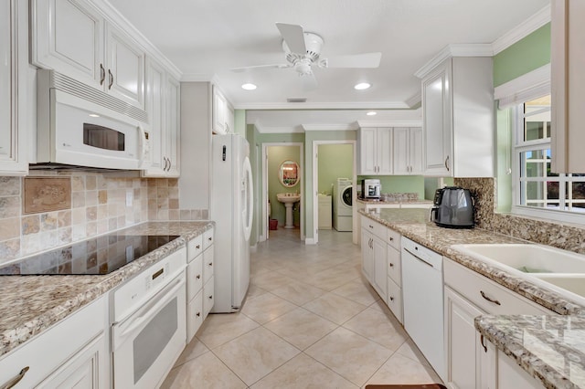 kitchen with white appliances, washer / clothes dryer, ceiling fan, white cabinets, and crown molding