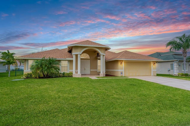 6496 NW Groveland Ter, Port Saint Lucie, FL 34986 - view of front facade with stucco siding, a yard, concrete driveway, and an attached garage