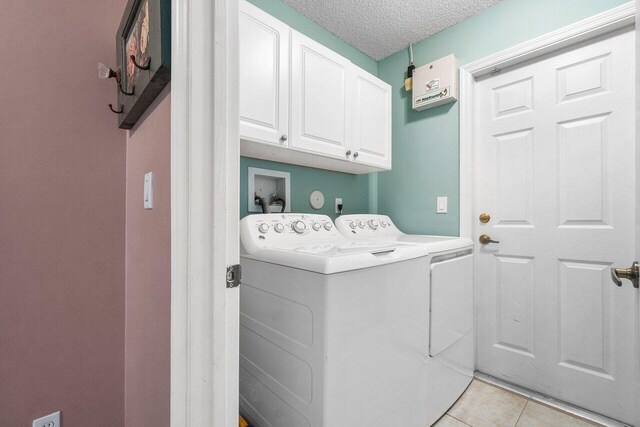 6346 Sand Hills Cir, Lake Worth, FL 33463 - clothes washing area featuring light tile patterned floors, cabinet space, a textured ceiling, and washer and dryer
