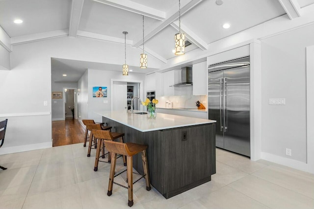 kitchen featuring modern cabinets, wall chimney exhaust hood, stainless steel appliances, white cabinetry, and a sink