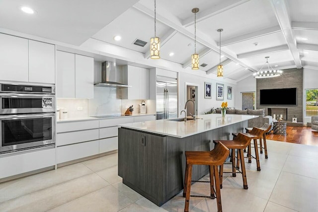 kitchen featuring appliances with stainless steel finishes, modern cabinets, wall chimney range hood, visible vents, and white cabinets