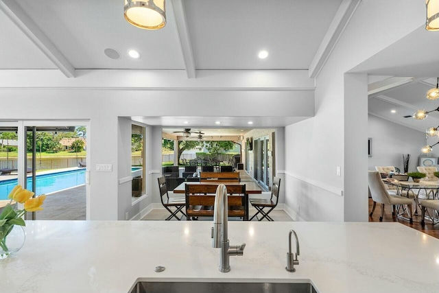 kitchen with beam ceiling, a sink, light stone countertops, ceiling fan, and recessed lighting