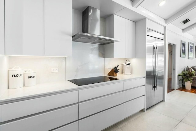 kitchen with white cabinetry, built in refrigerator, black electric stovetop, modern cabinets, and wall chimney exhaust hood